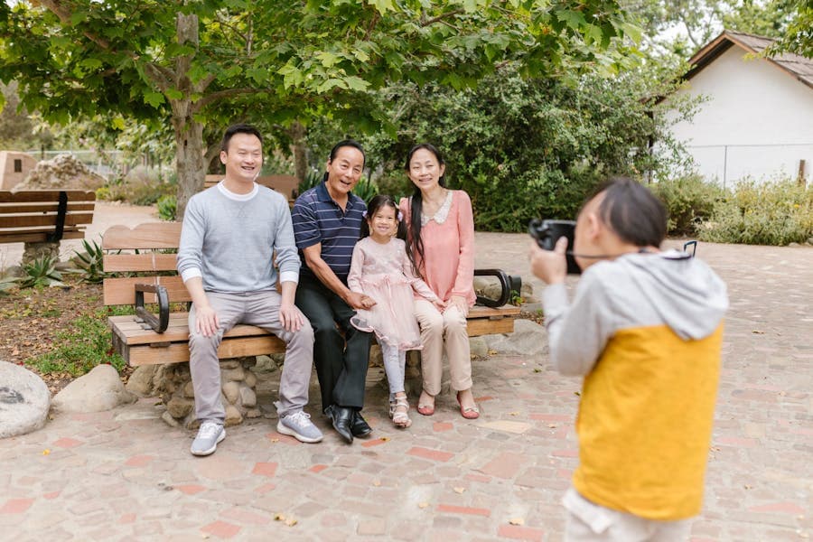 Three generations of a family posing for a photo together on a park bench