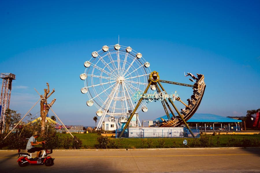A Ferris wheel and rides against a bright blue sky at a theme park