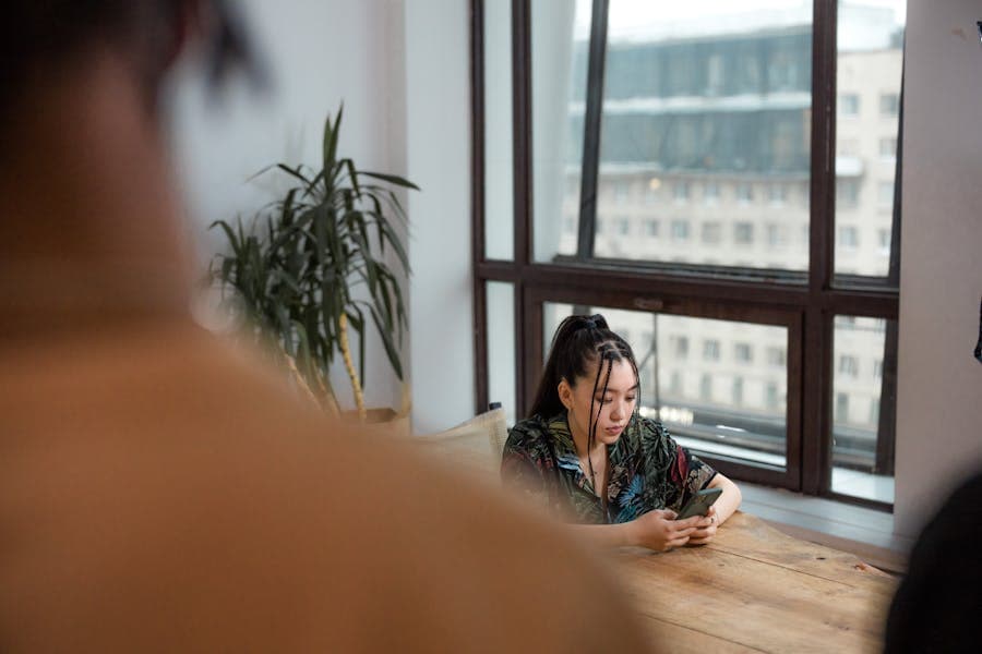 A person messaging family on a phone by a window